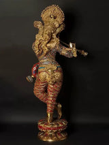 Brass Krishna figurine with raised hands playing flute, detailed red-and-gold outfit
