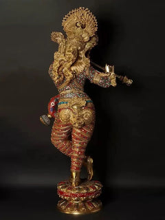 Brass Krishna figurine with raised hands playing flute, detailed red-and-gold outfit
