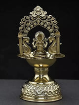 Brass diya showing seated Ganesha through arch, engraved base and flame bowl