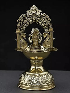 Brass diya showing seated Ganesha through arch, engraved base and flame bowl