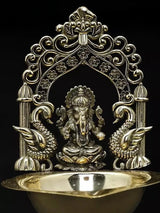 Brass Ganesha diya from front: ornate arch frame and sculpted deity at center