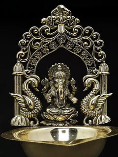 Brass Ganesha diya from front: ornate arch frame and sculpted deity at center