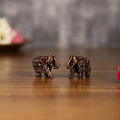 Two miniature copper elephant idols, side angle showing ornate carved patterns