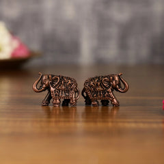 Pair of miniature copper elephant idols facing opposite directions, carved detailing