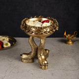 Brass vastu urli with fish feet, chained rim with dangling beads; flowers and candle