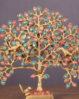 Close-up brass Kalpavriksha tree branches with multicolor round leaf ornaments and red base.