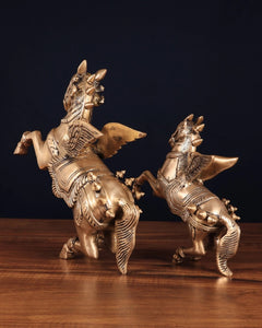 Brass winged horse statue pair in crouched pose, open wing and tail details