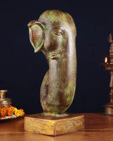 Brass Ganesha face showpiece, side profile with ornate forehead detailing and base.