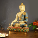 Tibetan Buddha statue seated on red-and-green base, blue robe with gold motifs