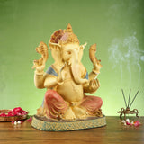 Ganesha brass statue in side view, four arms posed and gold details on face and crown