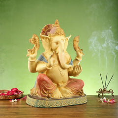 Ganesha brass statue in side view, four arms posed and gold details on face and crown
