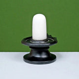 White shivling on glossy black round base, upright standing sculpture