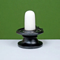 White shivling on glossy black round base, upright standing sculpture