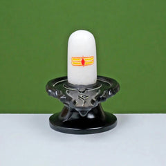 White shivling with orange-yellow emblem on black pedestal and circular base