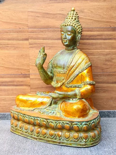 Brass Buddha sculpture, left palm raised, cross-legged on ornate round base with carvings