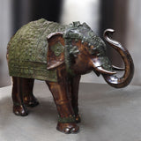 Large brass elephant standing sculpture with ornate green patina armor, raised trunk
