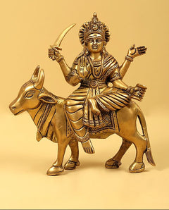 Brass Navadurga idol riding bull, front view with curved staff and ornamented hands