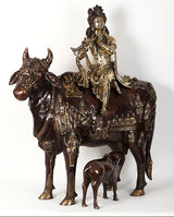 Krishna statue on cow, flute-playing pose with dark brown and gold finish