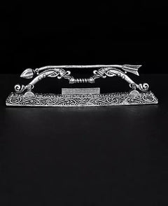 Brass arch-shaped dhanushe with serpent-like engravings and decorative ends