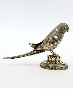 Small brass parrot statue with long tail, perched on lotus base, side profile