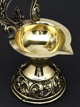 Close-up of brass diya bowl with embossed Ganesha and ornate base