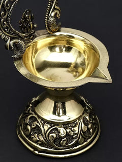 Close-up of brass diya bowl with embossed Ganesha and ornate base