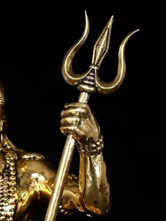 Close-up of Lord Shiva trident and upper arm on gold-toned brass idol