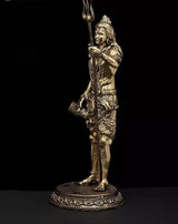 Brass Lord Shiva statue in profile, tall trident in hand, detailed patterned lower garment