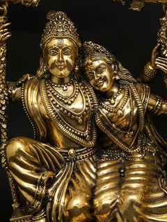 Radha-Krishna brass idol close-up with ornate crowns, jewelry, and calm faces.