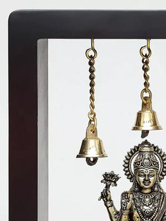 Brass wall hanging frame with hanging bell chain and partial Lakshmi idol view