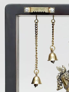 Close view of dangling bell chains and two bells above Lord Krishna wall hanging frame