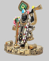 Small brass Krishna statue with black face, jeweled garlands, raised drum, animal-pattern base