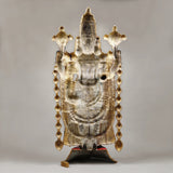 Back view of Tirupati Balaji idol with gold-tone plate, hanging chains, and pedestal base