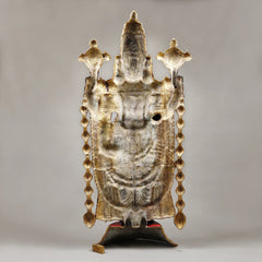 Back view of Tirupati Balaji idol with gold-tone plate, hanging chains, and pedestal base