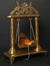 Brass jhoola with lotus and peacock motifs, ornate pillars, hanging chain cradle