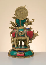 Brass Krishna sculpture on cow, rear view with ornate circular shield, teal and red