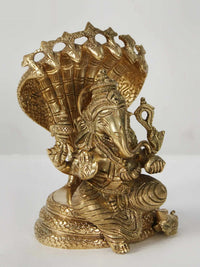 Brass Ganesha figurine seated on Sheshnag, three-quarter view with detailed ornaments