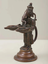 Brass Ganesha twin lamp figurine in side view, raised trunk, holding two dish lamps