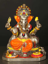 Brass Lord Ganesha figurine wearing orange dhoti, seated on a base with accessories