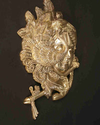 Brass relief Krishna face with detailed halo discs and flute finial on side