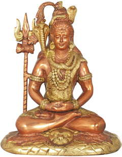 Gold brass Shiva idol seated cross-legged on tiger-skin base, trident beside