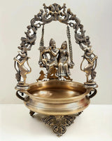 Brass urli with Radha Krishna on swing, ornate chain frame, 21-inch