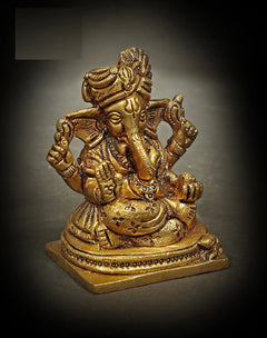 Brass Ganesha statue seated with raised arms and turban, ornate jewelry details (7.5 cm)