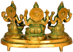 Back of brass Lakshmi-Ganesha-Saraswati figurines on green pedestal base