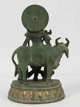 Back view of green patina brass Krishna statue with cow, circular halo and base
