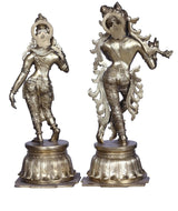 Brass Radha Krishna statue pair, full-body side views with ornate crowns and jewelry
