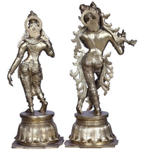 Brass Radha Krishna statue pair, full-body side views with ornate crowns and jewelry