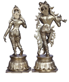Brass Radha Krishna statue pair, full-body side views with ornate crowns and jewelry