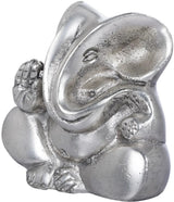 Close-up of small stylized Ganesha brass statue, metallic sheen, curved trunk and crown