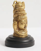 Brass Shiva head idol, side view with detailed curls and closed eyes, on dark base